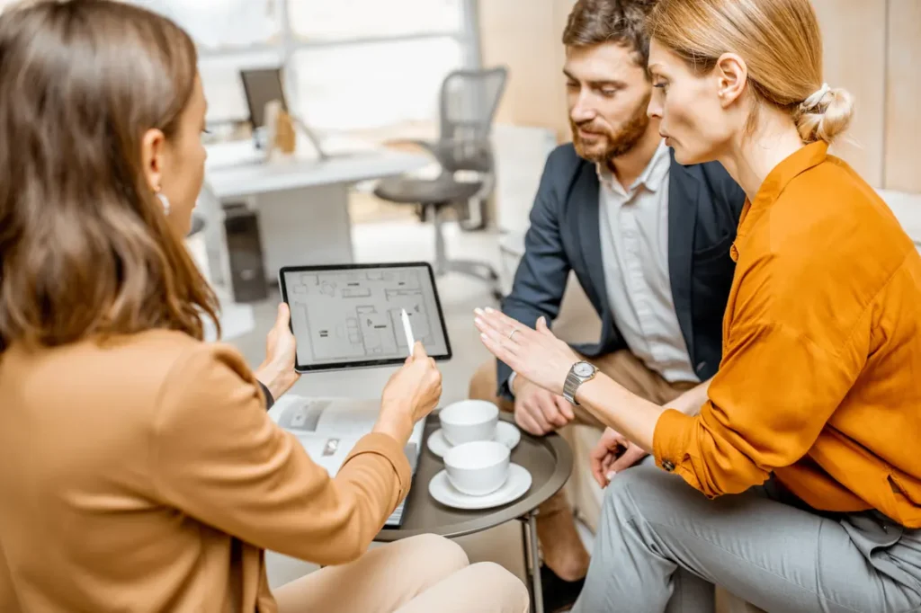 « Advisor presenting a plan on a tablet to two clients during a meeting »