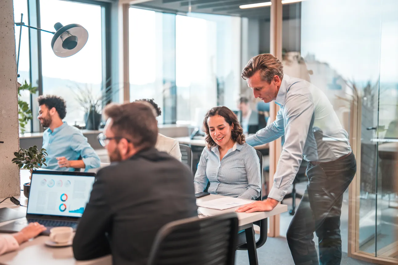 Manager supporting a colleague in an open office
